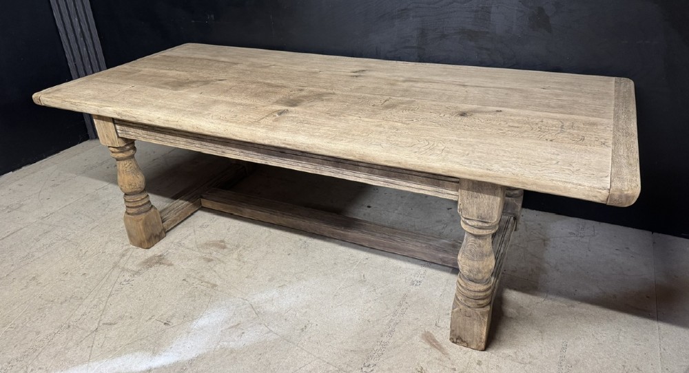 A large natural oak refectory dining table featuring turned legs, breadboard top ends, and an H-stretcher base.