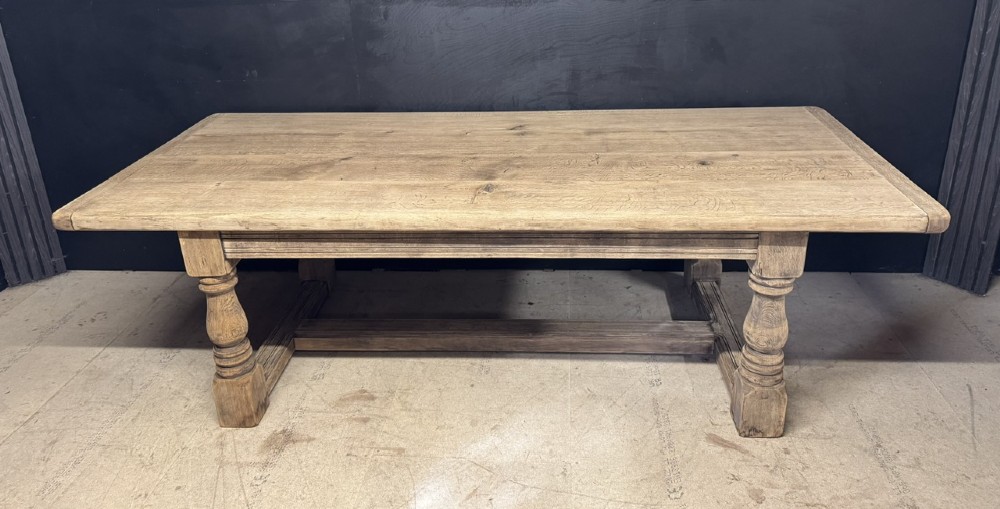 A large natural oak refectory dining table featuring turned legs, breadboard top ends, and an H-stretcher base. View IV