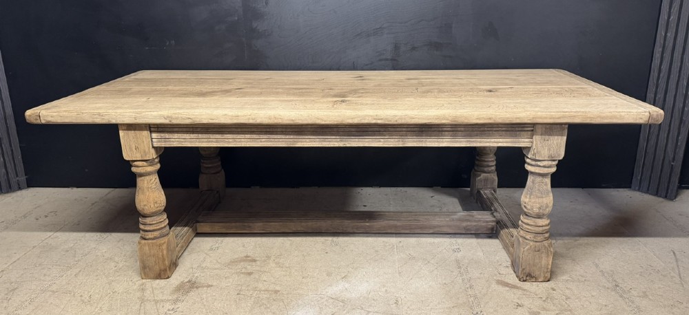 A large natural oak refectory dining table featuring turned legs, breadboard top ends, and an H-stretcher base. View V