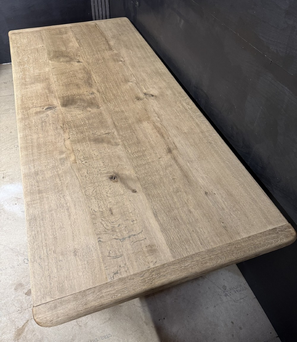 A large natural oak refectory dining table featuring turned legs, breadboard top ends, and an H-stretcher base. View VI