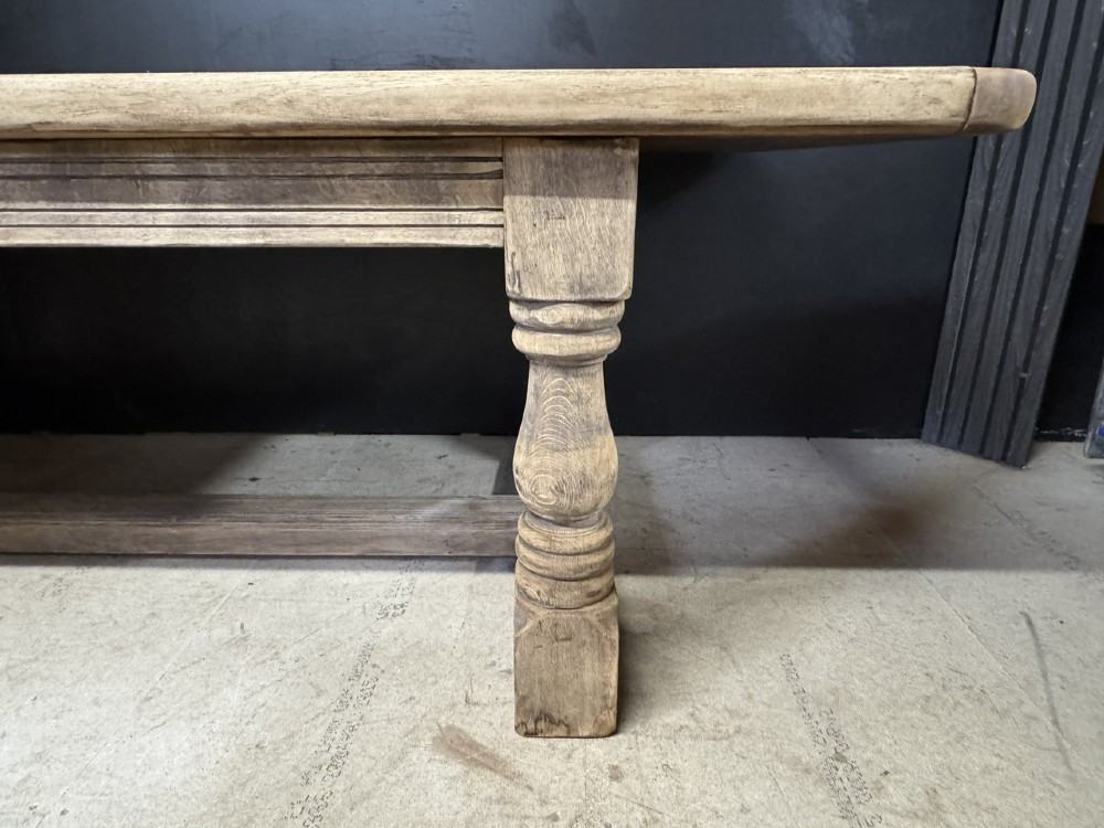 A large natural oak refectory dining table featuring turned legs, breadboard top ends, and an H-stretcher base. View XI