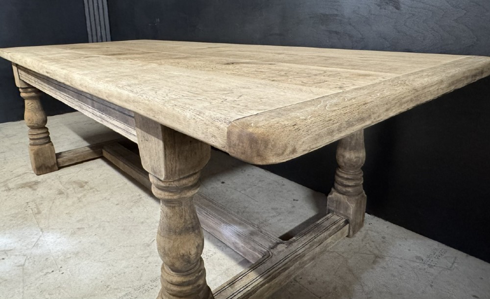 A large natural oak refectory dining table featuring turned legs, breadboard top ends, and an H-stretcher base. View XIV