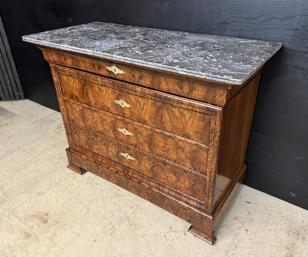A 19th-century French Louis Philippe burr walnut commode featuring a grey marble top, four drawers, and ornate brass keyhole escutcheons. View IV
