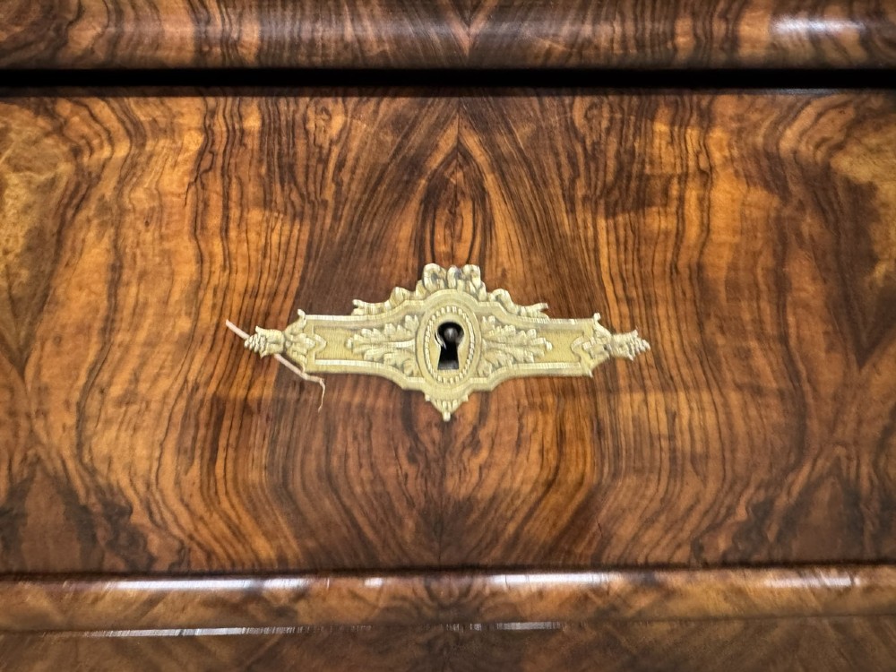A 19th-century French Louis Philippe burr walnut commode featuring a grey marble top, four drawers, and ornate brass keyhole escutcheons. View VII