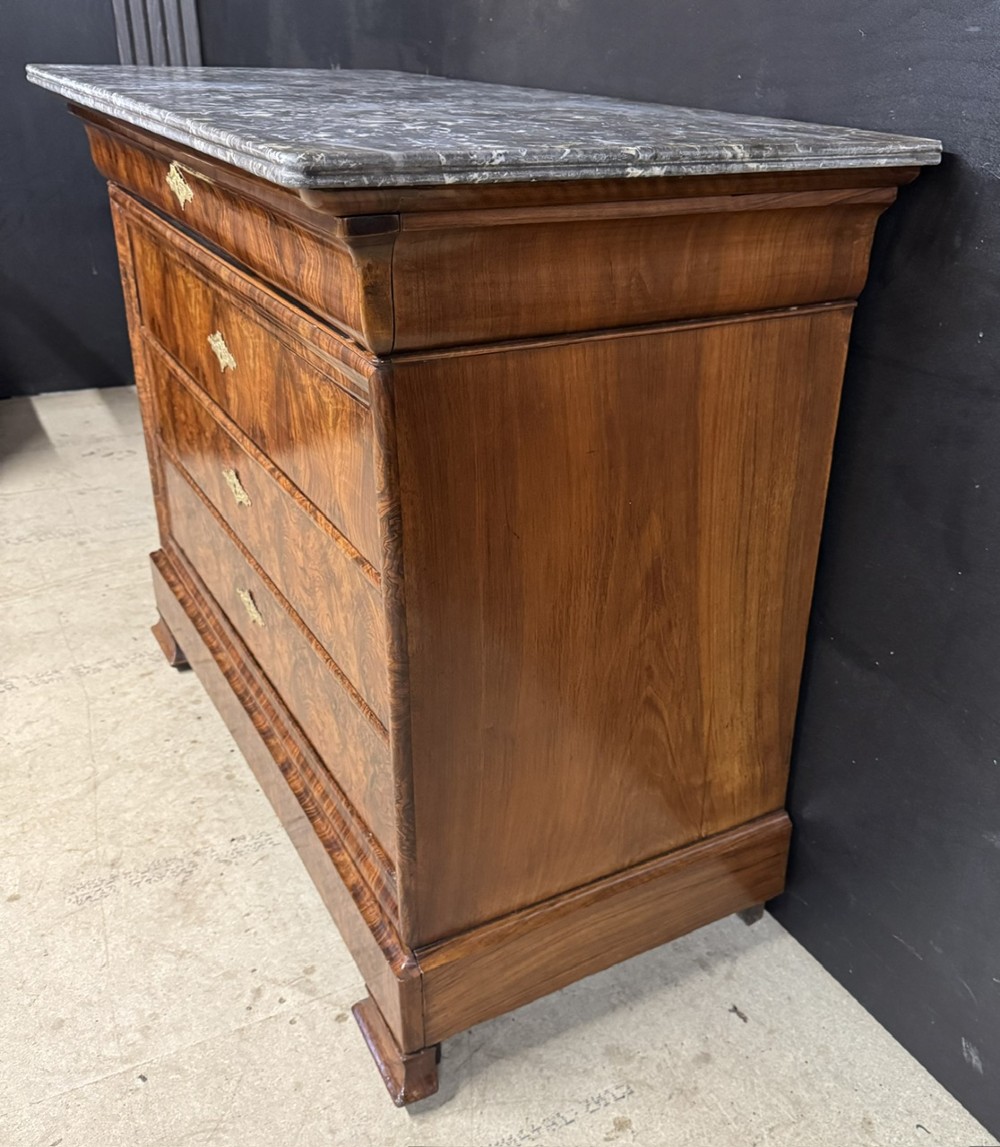 A 19th-century French Louis Philippe burr walnut commode featuring a grey marble top, four drawers, and ornate brass keyhole escutcheons. View XII