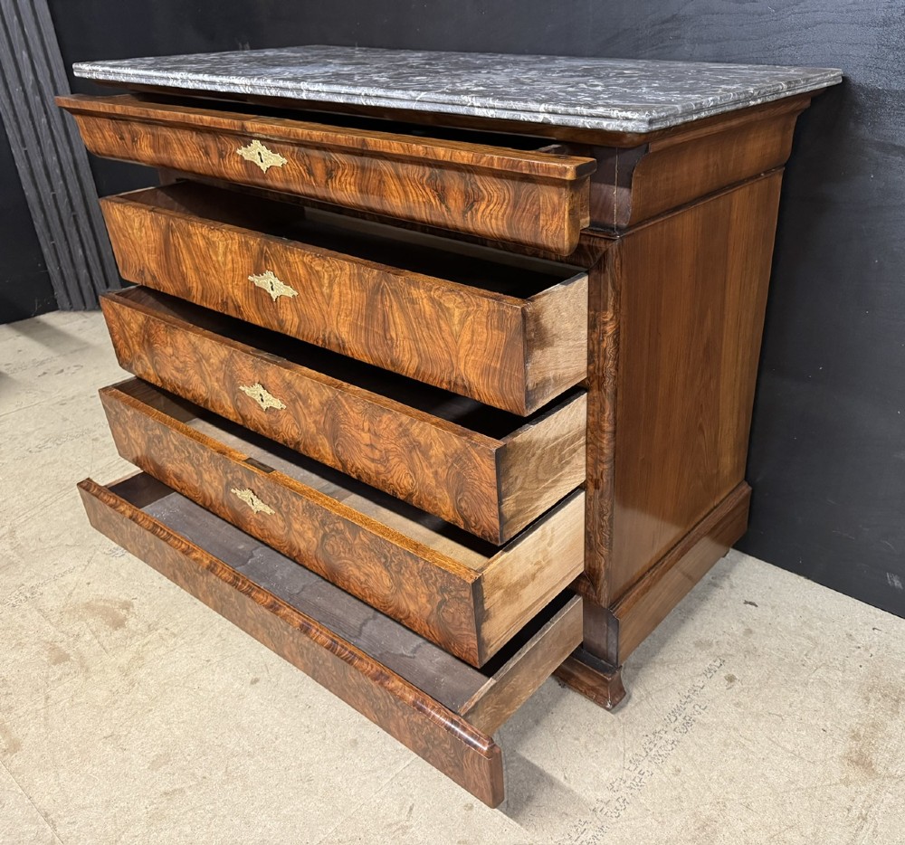A 19th-century French Louis Philippe burr walnut commode featuring a grey marble top, four drawers, and ornate brass keyhole escutcheons. View XV