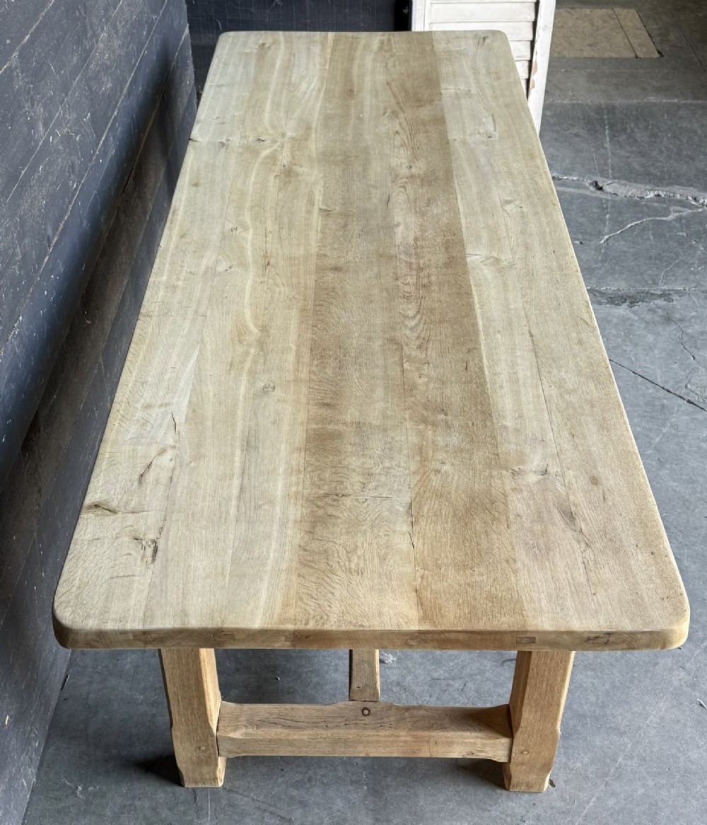 A large rectangular natural oak farmhouse dining table featuring a thick plank top, square legs, and an H-stretcher base. View III