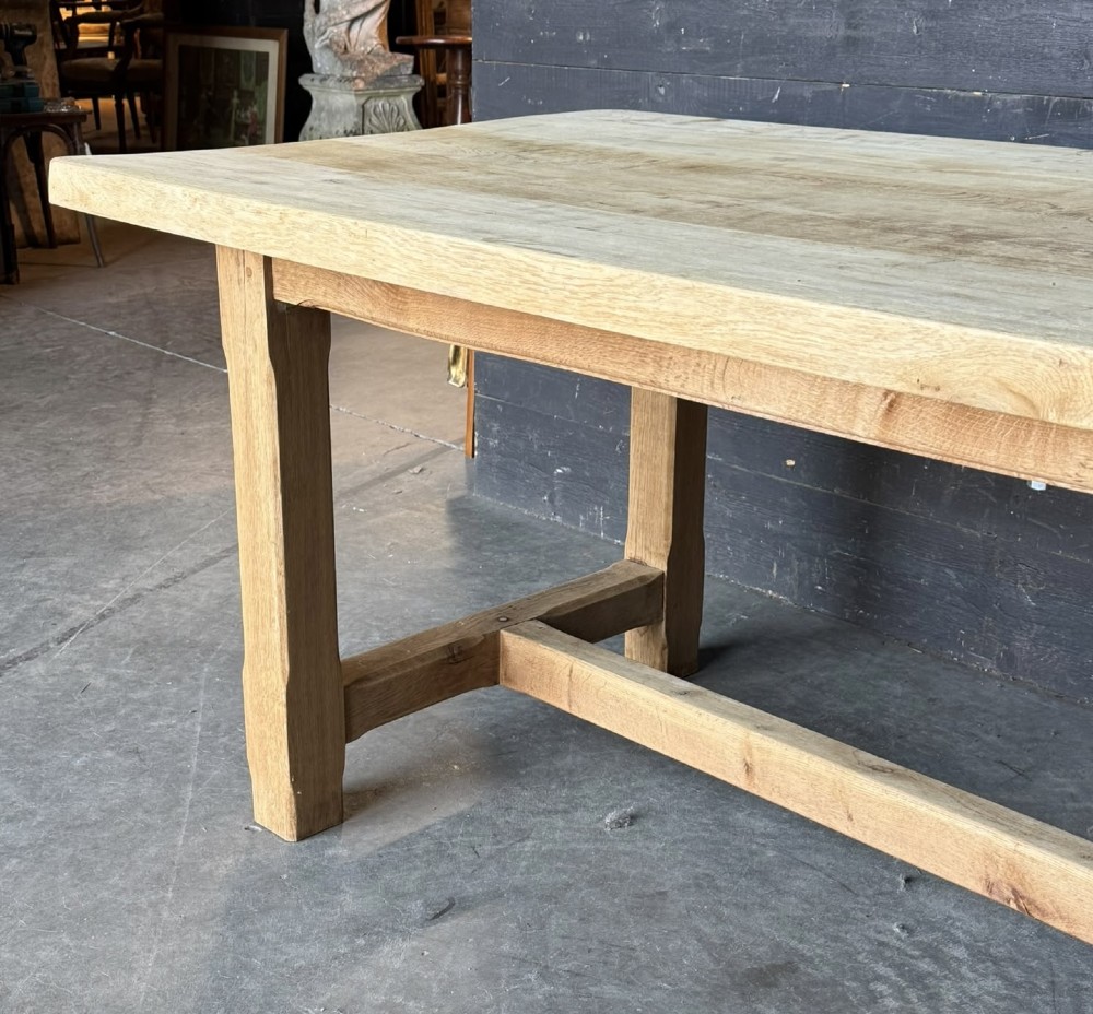 A large rectangular natural oak farmhouse dining table featuring a thick plank top, square legs, and an H-stretcher base. View X