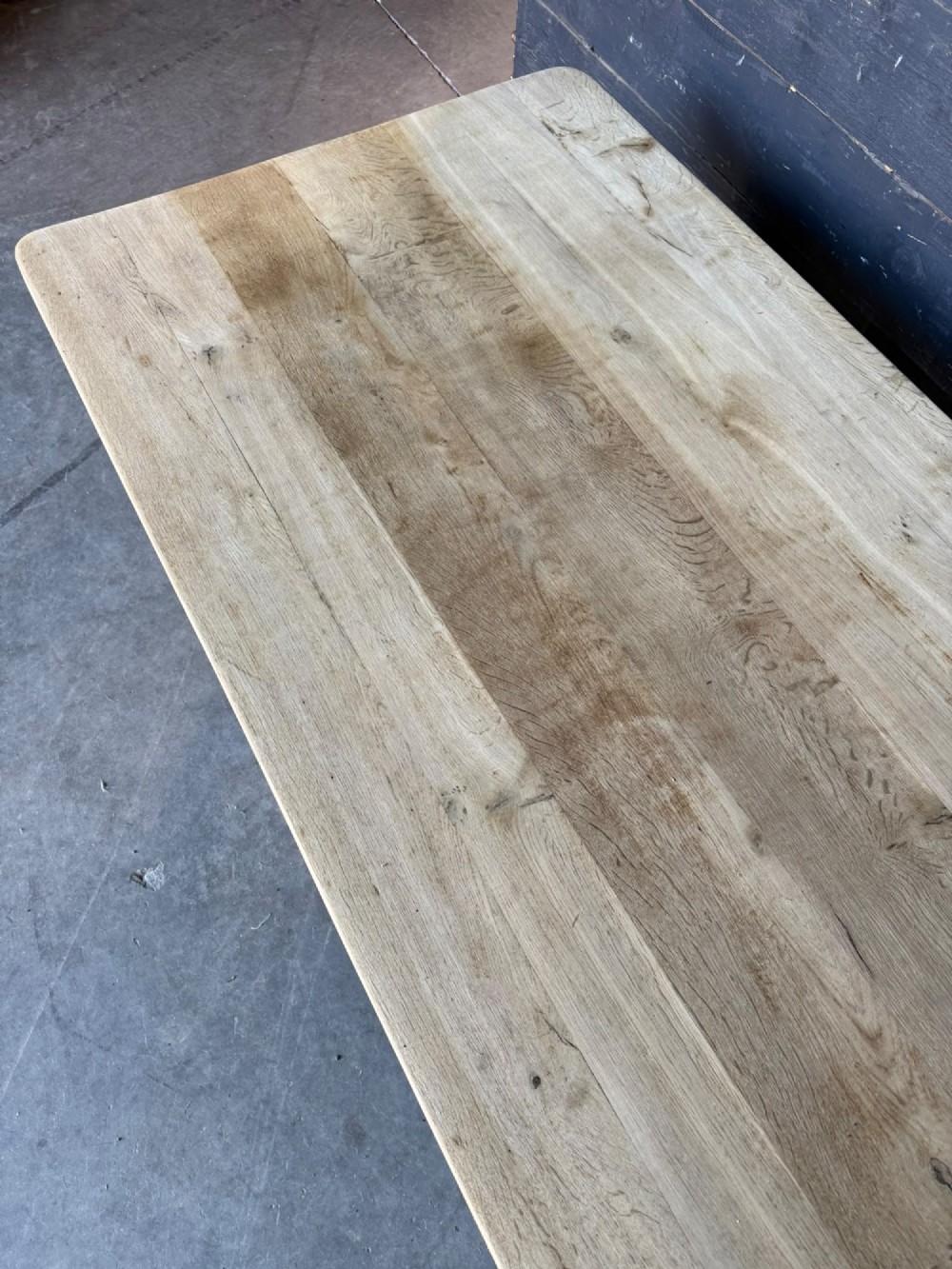 A large rectangular natural oak farmhouse dining table featuring a thick plank top, square legs, and an H-stretcher base. View XI