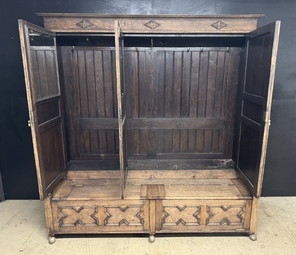 A large carved oak hall bench featuring a high back with three cupboard doors, geometric diamond panelling, and a lift-top storage seat. View II
