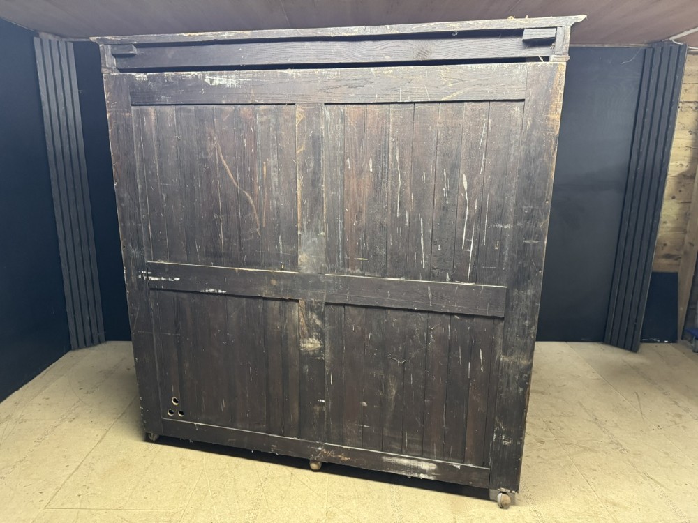 A large carved oak hall bench featuring a high back with three cupboard doors, geometric diamond panelling, and a lift-top storage seat. View XIII
