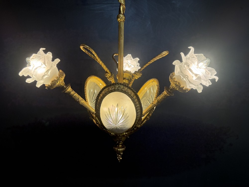 An ornate French gilt bronze chandelier featuring scroll arms, cut glass inserts, and ruffled white glass flower shades. View IV