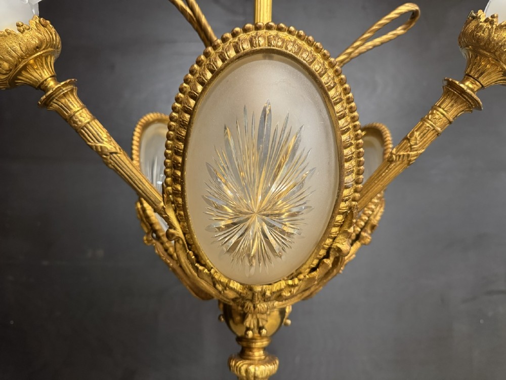 An ornate French gilt bronze chandelier featuring scroll arms, cut glass inserts, and ruffled white glass flower shades. View V