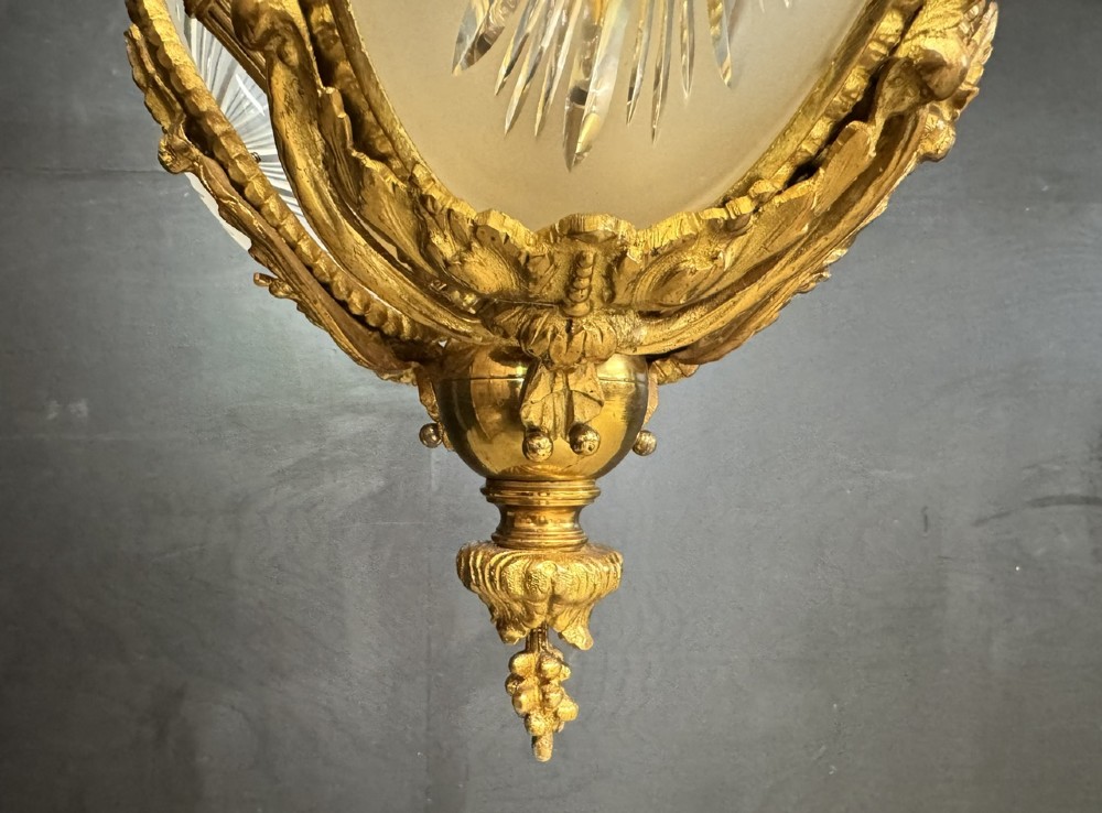An ornate French gilt bronze chandelier featuring scroll arms, cut glass inserts, and ruffled white glass flower shades. View VI