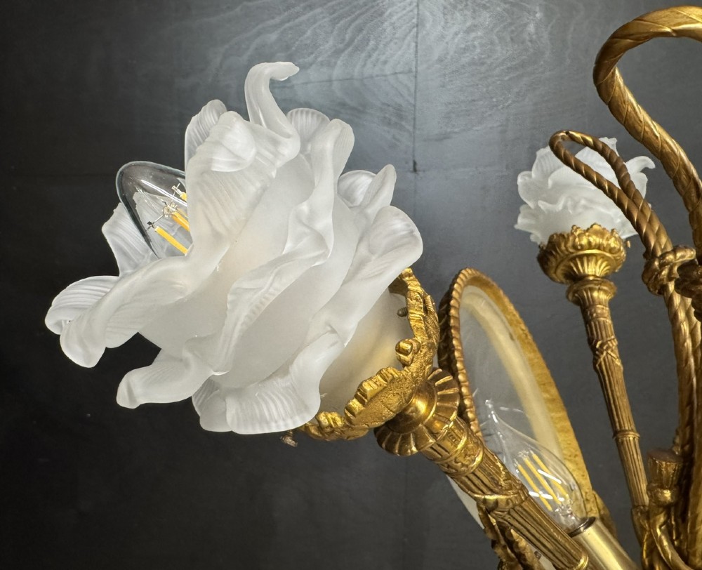 An ornate French gilt bronze chandelier featuring scroll arms, cut glass inserts, and ruffled white glass flower shades. View VII
