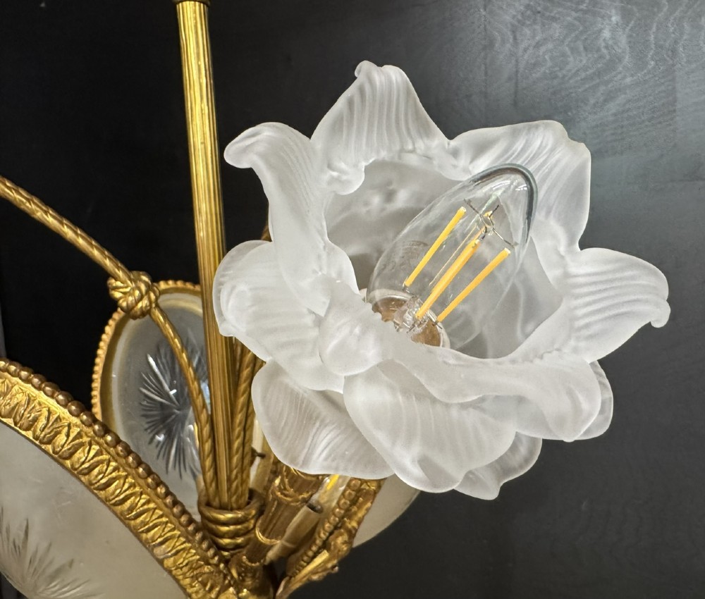 An ornate French gilt bronze chandelier featuring scroll arms, cut glass inserts, and ruffled white glass flower shades. View VIII