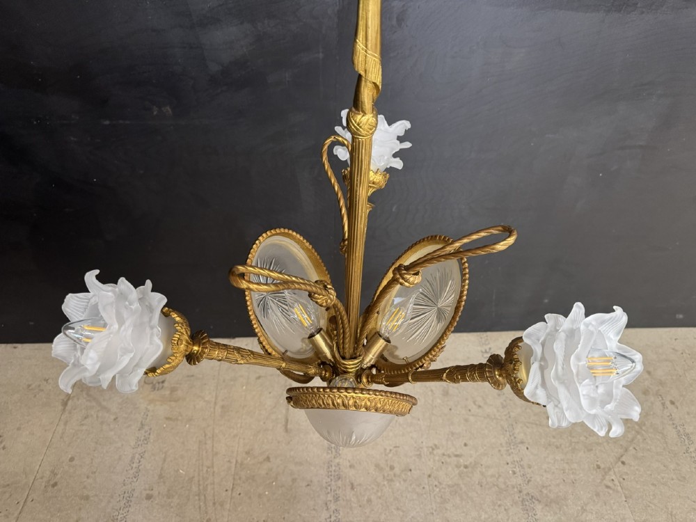 An ornate French gilt bronze chandelier featuring scroll arms, cut glass inserts, and ruffled white glass flower shades. View IX