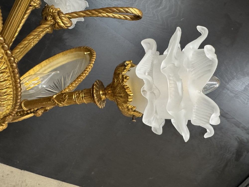 An ornate French gilt bronze chandelier featuring scroll arms, cut glass inserts, and ruffled white glass flower shades. View XI