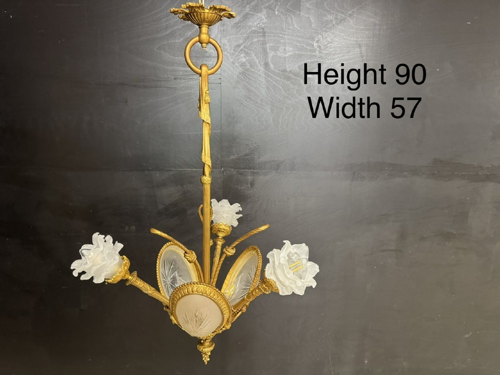 An ornate French gilt bronze chandelier featuring scroll arms, cut glass inserts, and ruffled white glass flower shades. View XII
