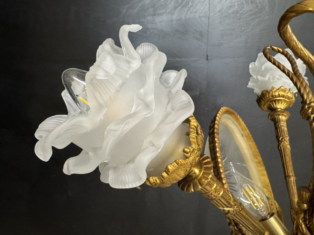 An ornate French gilt bronze chandelier featuring scroll arms, cut glass inserts, and ruffled white glass flower shades. View XIII