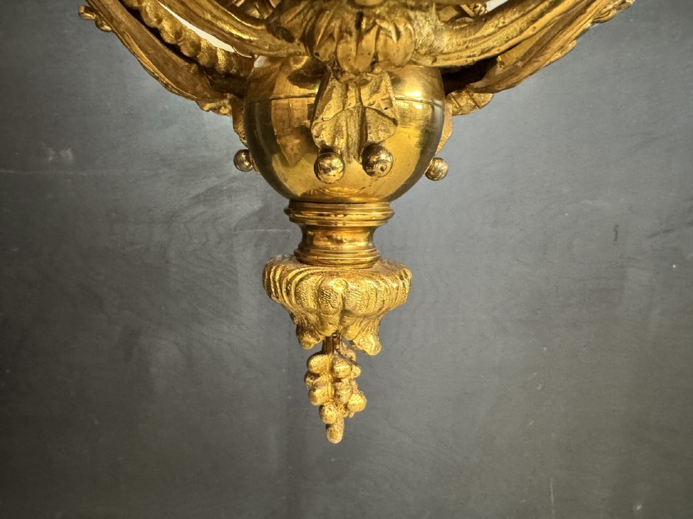 An ornate French gilt bronze chandelier featuring scroll arms, cut glass inserts, and ruffled white glass flower shades. View XIV