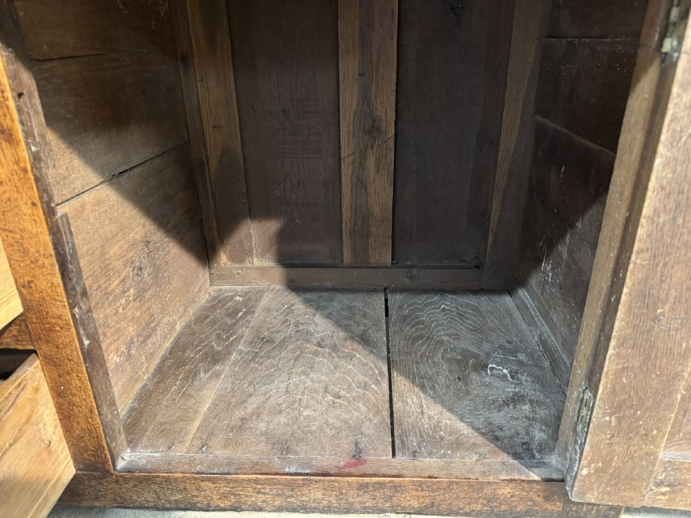 A Georgian Welsh oak dresser base with multiple drawers and two panelled cupboard doors featuring brass drop handles. View VII