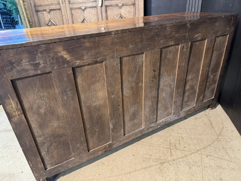 A Georgian Welsh oak dresser base with multiple drawers and two panelled cupboard doors featuring brass drop handles. View XV