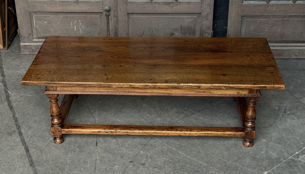 A low rectangular solid oak coffee table featuring a thick plank top, turned legs, and a low stretcher base.