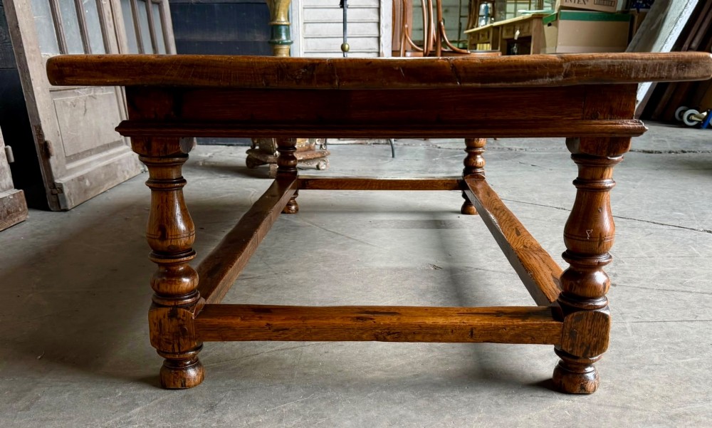 A low rectangular solid oak coffee table featuring a thick plank top, turned legs, and a low stretcher base. View V