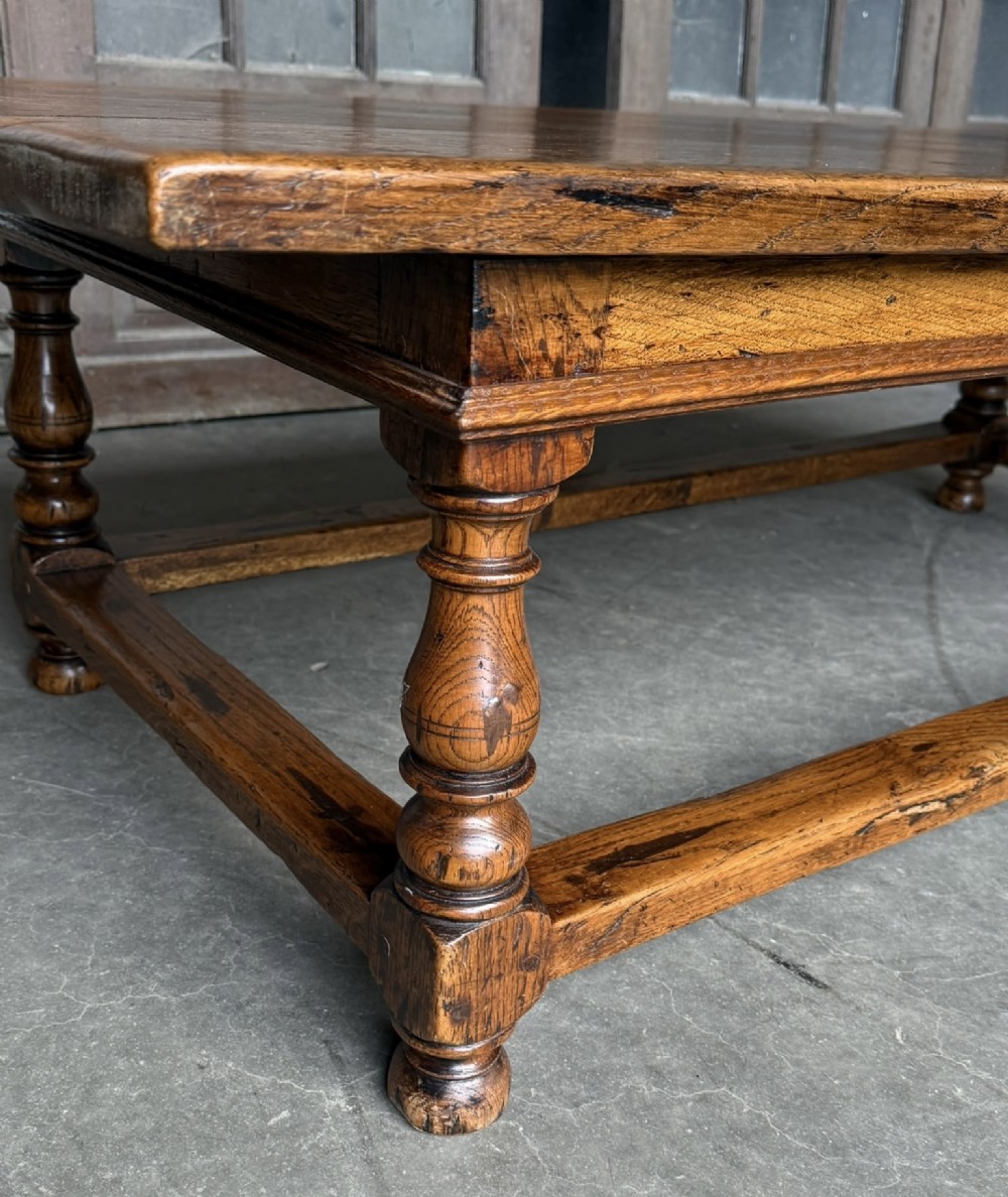 A low rectangular solid oak coffee table featuring a thick plank top, turned legs, and a low stretcher base. View VI