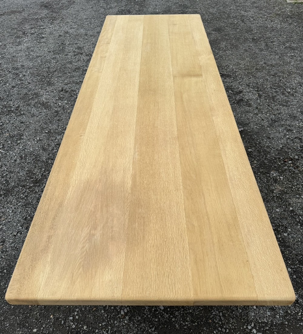 A three-metre-long natural oak trestle dining table featuring a solid plank top and a pegged central stretcher base. View II