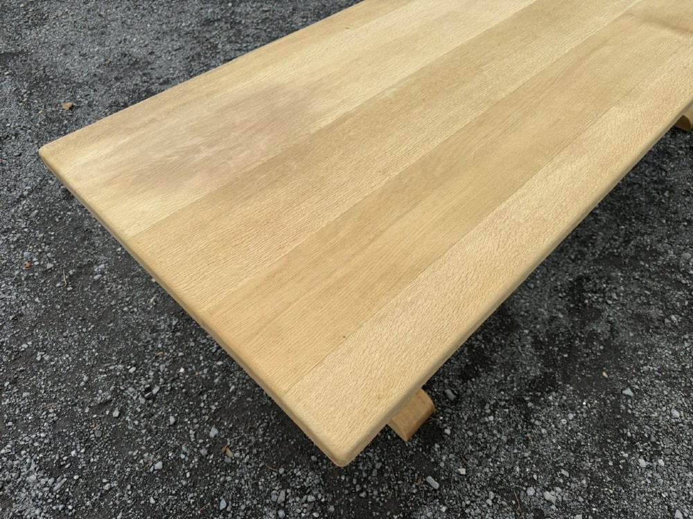 A three-metre-long natural oak trestle dining table featuring a solid plank top and a pegged central stretcher base. View VII