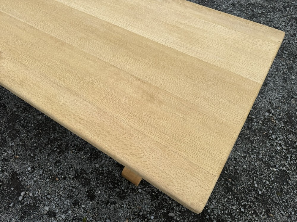 A three-metre-long natural oak trestle dining table featuring a solid plank top and a pegged central stretcher base. View VIII