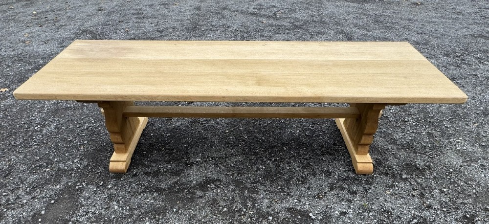 A three-metre-long natural oak trestle dining table featuring a solid plank top and a pegged central stretcher base. View IX