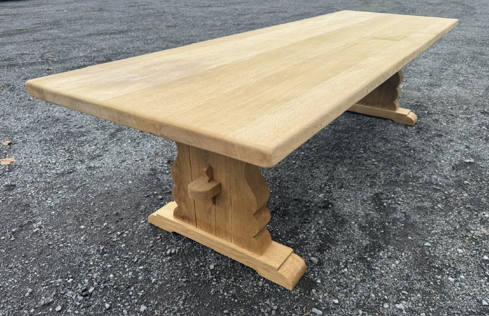 A three-metre-long natural oak trestle dining table featuring a solid plank top and a pegged central stretcher base. View XIV