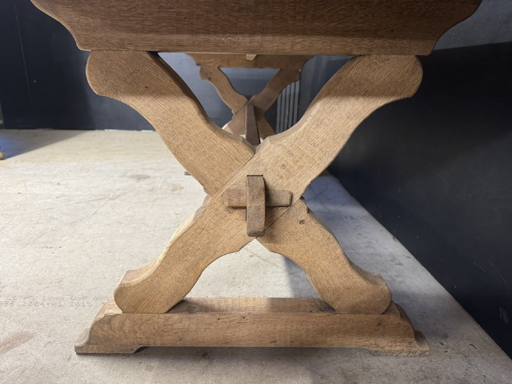 A rustic light oak dining table featuring a thick plank top supported by X-frame trestle legs and a pegged central stretcher. View V