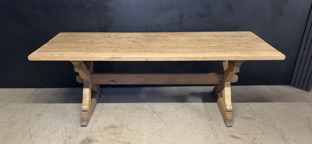 A rustic light oak dining table featuring a thick plank top supported by X-frame trestle legs and a pegged central stretcher. View VIII