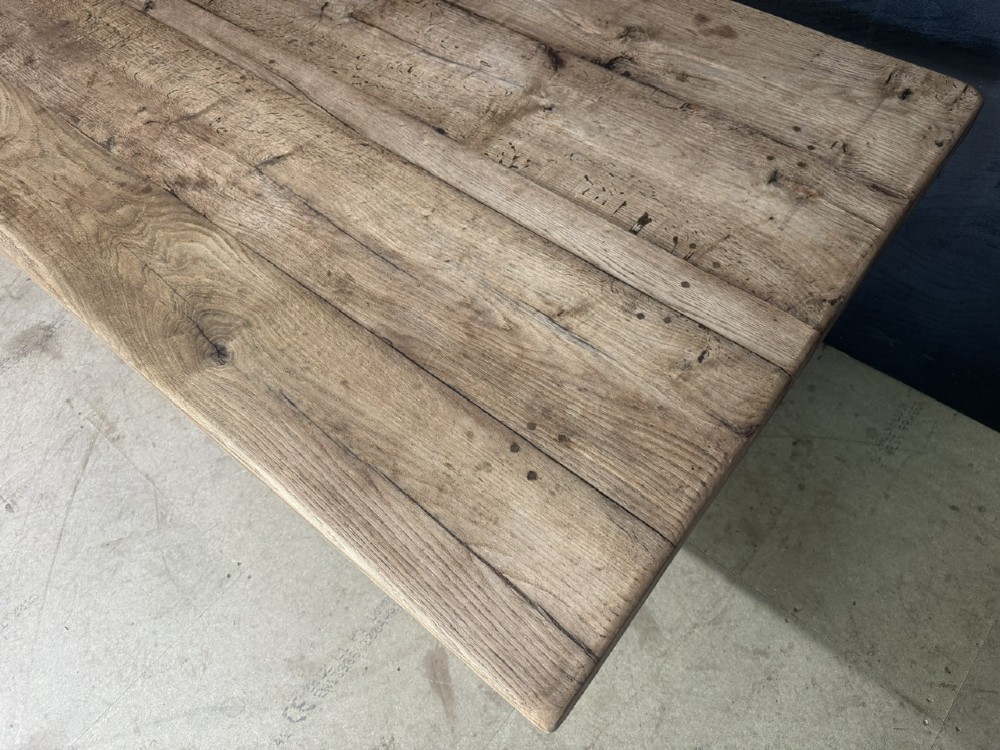 A large oak farmhouse dining table featuring a solid plank top resting on trestle end supports and a keyed stretcher. View IV