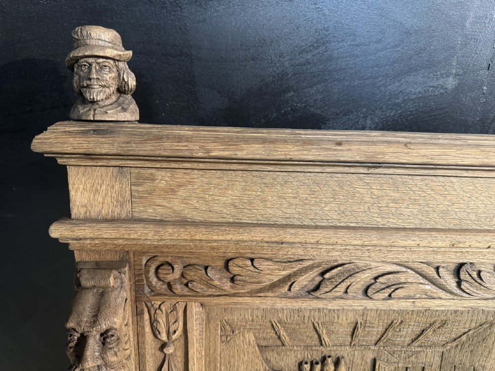 A French carved oak hall bench featuring relief panels depicting tavern scenes, lion figure armrests, and mask carvings on the base. View VII