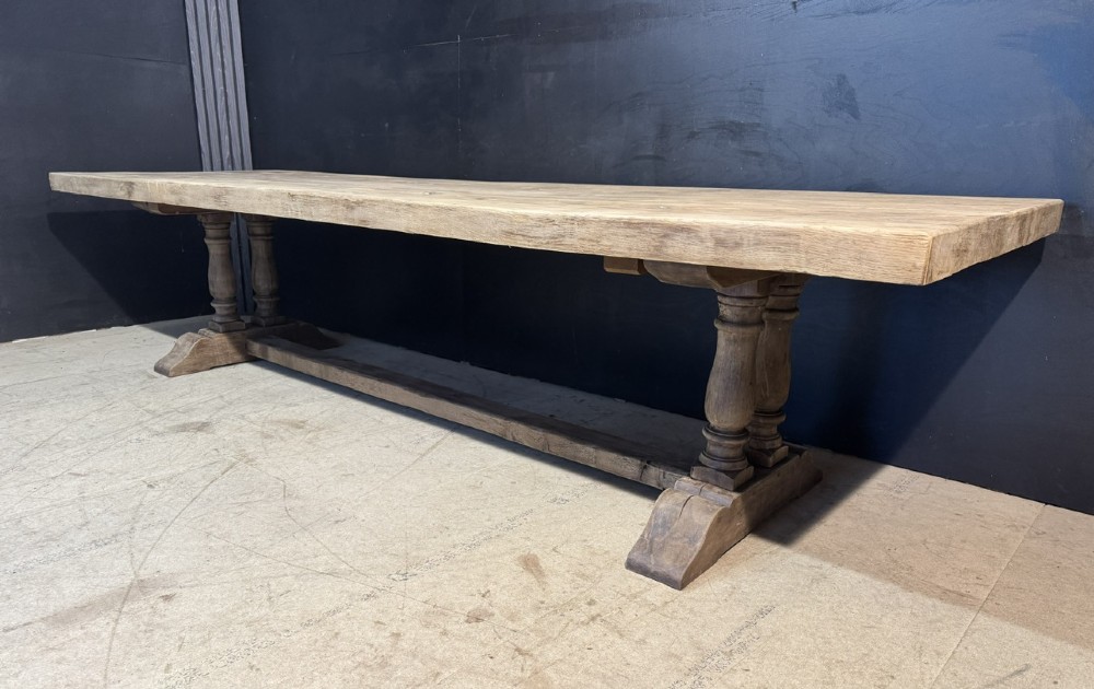 An extra long natural oak refectory dining table featuring a timber plank top supported by twin turned baluster trestle legs connected by a floor-level stretcher. View II