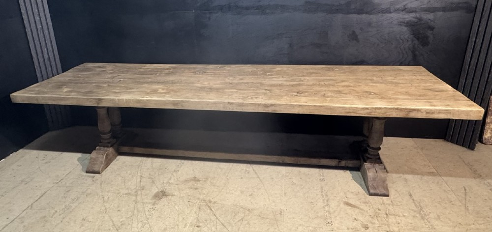 An extra long natural oak refectory dining table featuring a timber plank top supported by twin turned baluster trestle legs connected by a floor-level stretcher. View IX