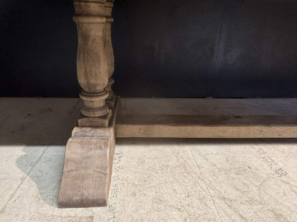 An extra long natural oak refectory dining table featuring a timber plank top supported by twin turned baluster trestle legs connected by a floor-level stretcher. View XI
