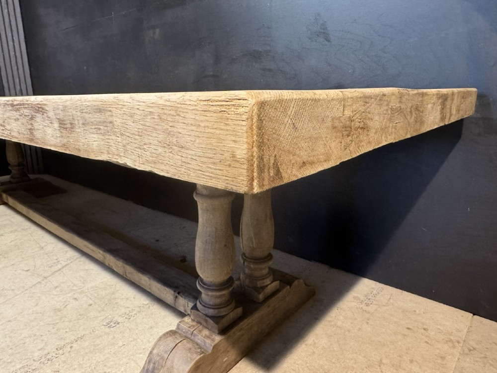 An extra long natural oak refectory dining table featuring a timber plank top supported by twin turned baluster trestle legs connected by a floor-level stretcher. View XII