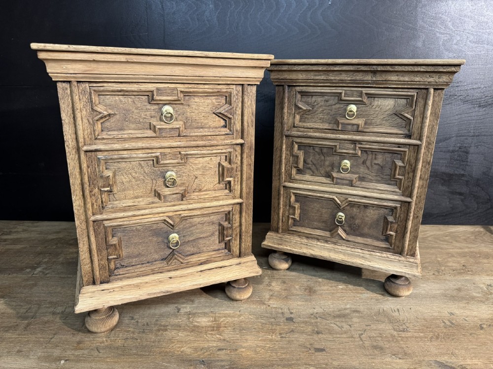 A pair of light oak three-drawer bedside chests with geometric carved drawer fronts, brass ring handles, and turned bun feet. View II