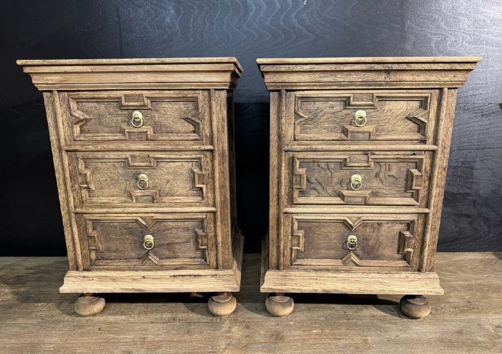 A pair of light oak three-drawer bedside chests with geometric carved drawer fronts, brass ring handles, and turned bun feet. View IV