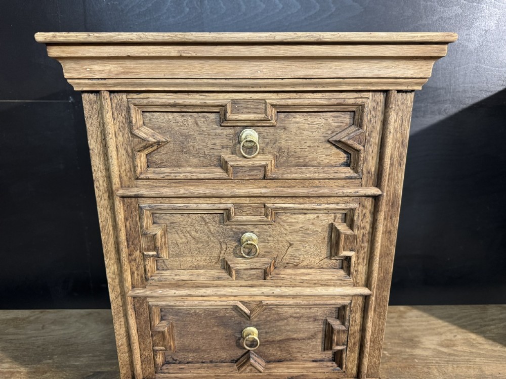 A pair of light oak three-drawer bedside chests with geometric carved drawer fronts, brass ring handles, and turned bun feet. View IX