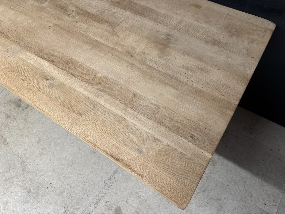 A large bleached oak farmhouse dining table featuring a thick plank top supported by a trestle base with a centre stretcher. View V