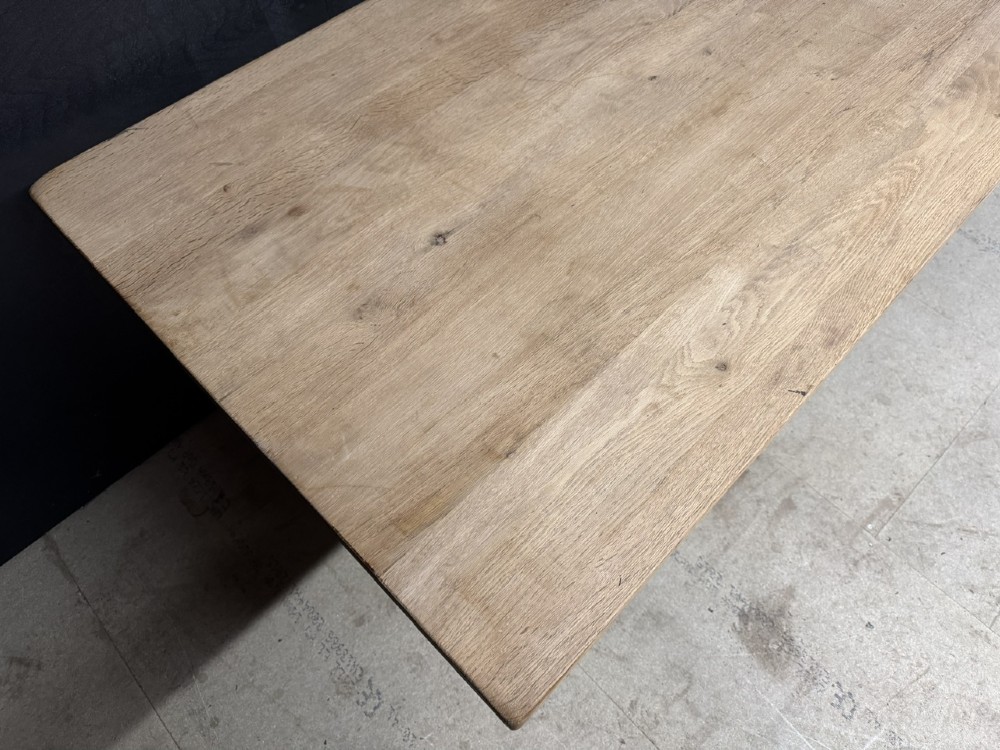 A large bleached oak farmhouse dining table featuring a thick plank top supported by a trestle base with a centre stretcher. View VI