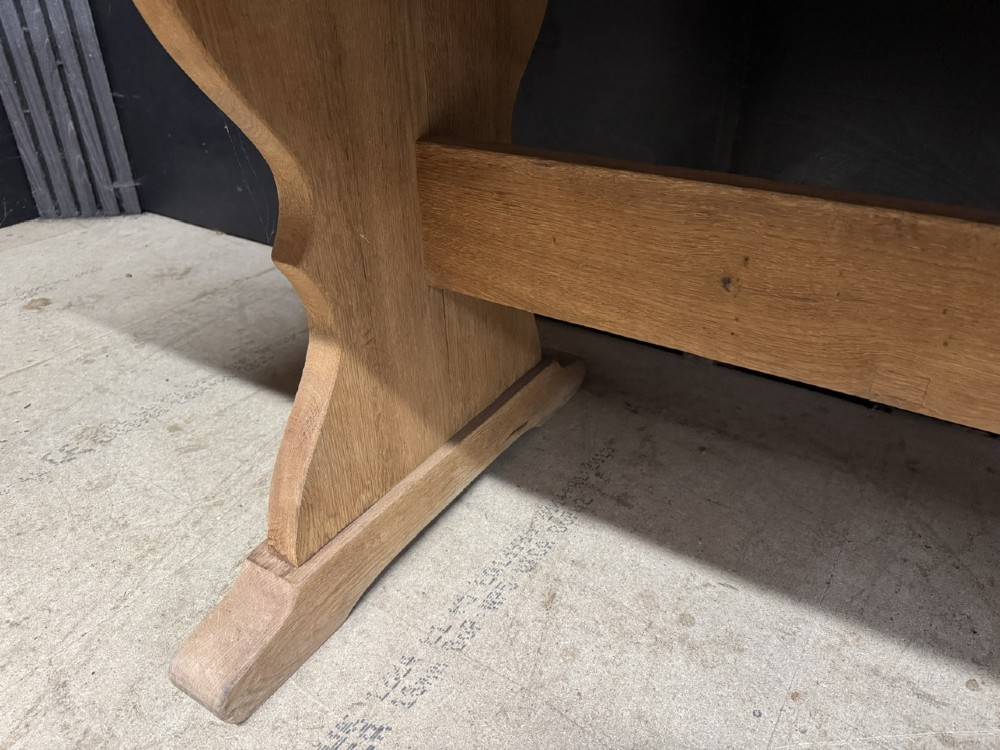A large bleached oak farmhouse dining table featuring a thick plank top supported by a trestle base with a centre stretcher. View X