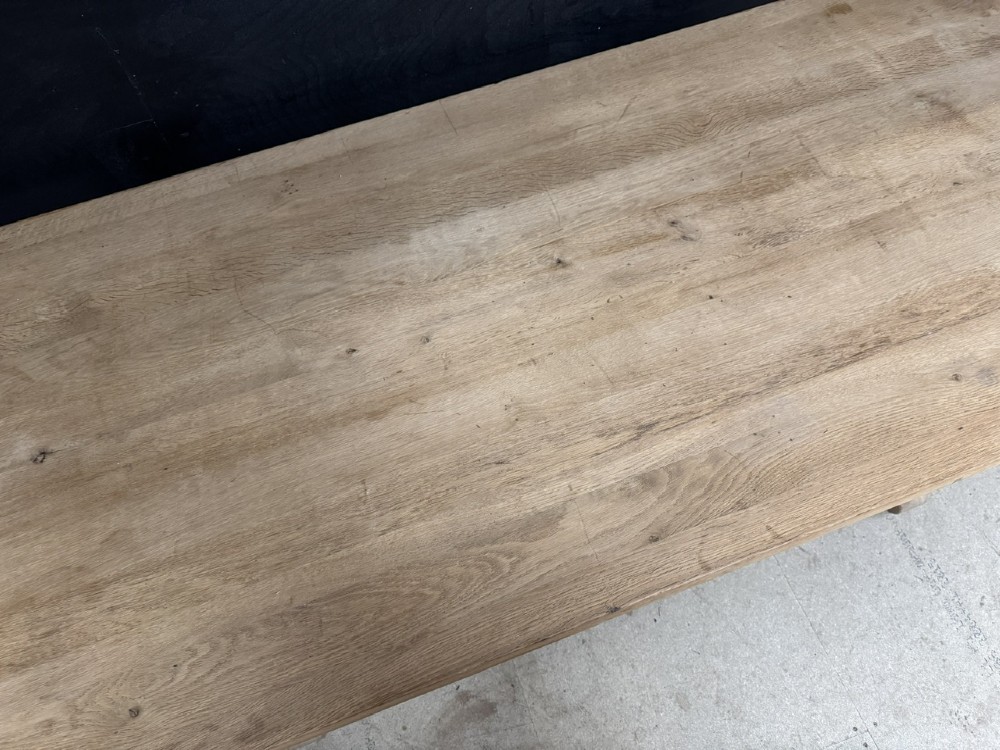 A large bleached oak farmhouse dining table featuring a thick plank top supported by a trestle base with a centre stretcher. View XI